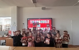 Grupa dzieci stoi na tle dekoracji z napisem &bdquo;Pasowanie na czytelnika&rdquo;. Dzieci trzymają w rękach książki.