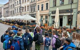 Grupa uczni&oacute;w z uwagą przygląda się architekturze Torunia